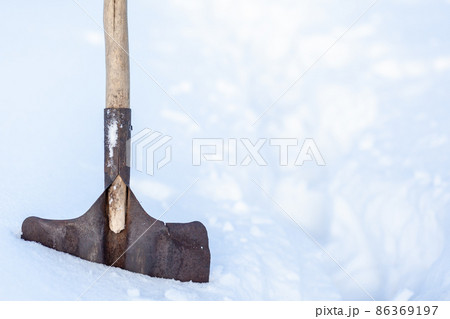 Metal shovel stuck with snow close-up. Snow removal in winter after a snowfall. Clearing snow in the home area. Metal shovel stuck with snow close-up. Snow removal in winter after a snowfall. Clearing snow in the home area. 86369197