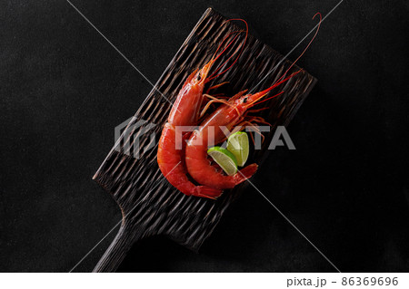 Top view of two royal red shrimps with lime on wooden board Top view of two royal red shrimps with lime on wooden board 86369696