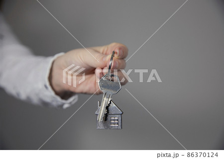 Real estate agent with house model and keys, selling house,property owner mortgage concept with copy space on gray background 86370124