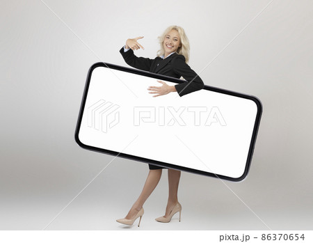 Full body length shot of happy businesswoman carrying big smartphone with blank screen and pointing at gadget screen Full body length shot of happy businesswoman carrying big smartphone with blank screen and pointing at gadget screen 86370654