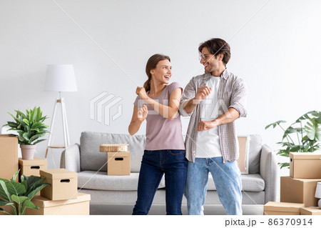 Happy satisfied caucasian man and wife celebrating buying of new apartment, dancing in room interior Happy satisfied caucasian man and wife celebrating buying of new apartment, dancing in room interior 86370914