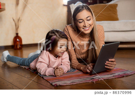 Smiling woman and girl using tablet at home 86370996