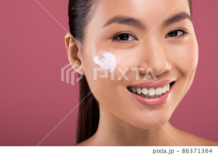 Smiling asian woman with moisturizer cream on her cheeks Smiling asian woman with moisturizer cream on her cheeks 86371364