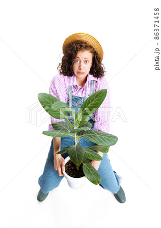 High angle view of young scared girl, female gardener in work uniform and gumboots isolated on white background. Concept of job, emotions, agronomy High angle view of young scared girl, female gardener in work uniform and gumboots isolated on white background. Concept of job, emotions, agronomy 86371458