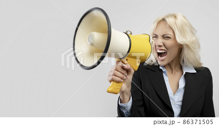 Angry irritated female businesswoman in formal wear screaming in megaphone and looking aside at free space Angry irritated female businesswoman in formal wear screaming in megaphone and looking aside at free space 86371505