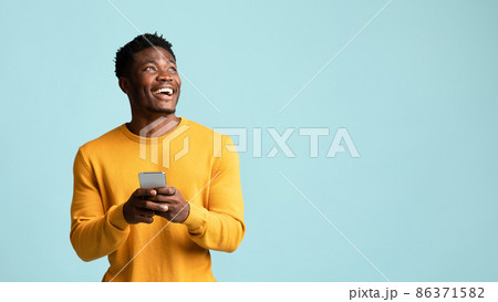 Cheerful black man using smartphone, looking at copy space 86371582
