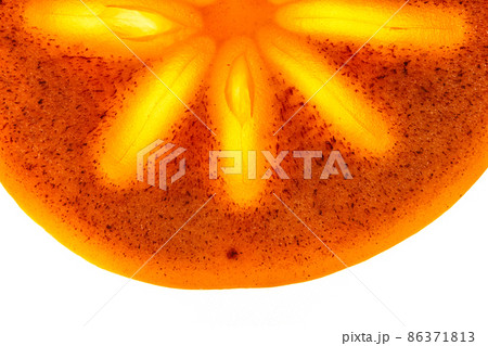 Close-up of a piece of fresh ripe persimmon, half a round slice on an isolated white background.Bright light in the middle of the fruit. High quality photo 86371813
