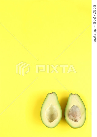 Two halfs of avocado with and without seed on yellow background. Two halfs of avocado with and without seed on yellow background. 86372958