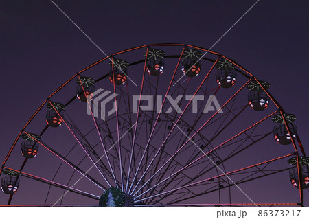 Closeup colorful Ferris wheel against sunset very peri sky. Abstract futuristic urban architecture, motion blur, selective focus Closeup colorful Ferris wheel against sunset very peri sky. Abstract futuristic urban architecture, motion blur, selective focus 86373217