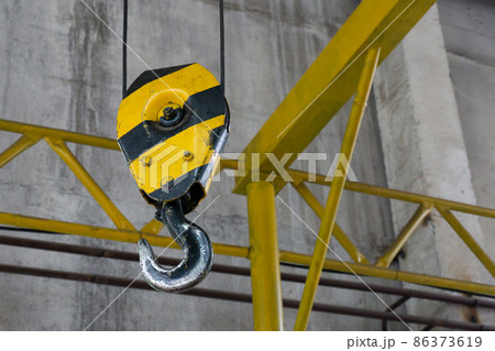 Crane hook hanging on steel ropes. Large crane in the workshop. Crane hook hanging on steel ropes. Large crane in the workshop. 86373619