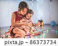 Little sisters having fun at home with chrismass lights. 86373734