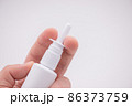 Holding nasal spray between fingers isolated on white background 86373759