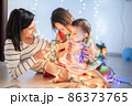 Mother with her daughters play with christmass lights 86373765