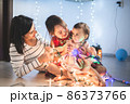 Mother with her daughters play with christmass lights 86373766