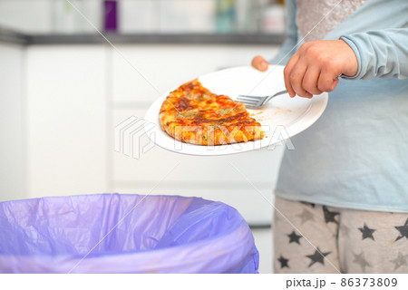 child who throws food in the trash, thus wasting it. 86373809