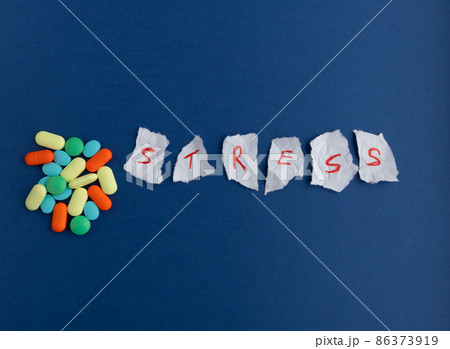 Scraps of paper with red letters on a blue background and pills.The concept of reducing, relieving and managing stress. Scraps of paper with red letters on a blue background and pills.The concept of reducing, relieving and managing stress. 86373919