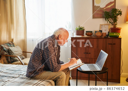 Elderly man using laptop at home 86374652