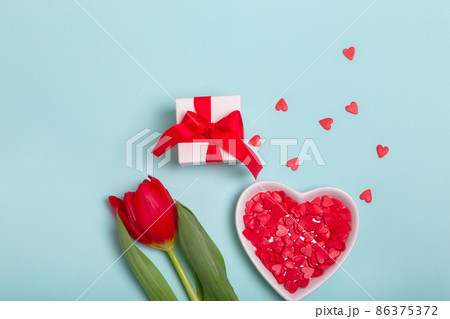 Craft gift box with a red ribbon, flowers and a paper hearts on a blue background for Valentine's Day. Mother's Day. 86375372