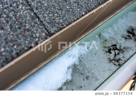 Ice and snow building up inside a rooftop gutter system on a residential house Ice and snow building up inside a rooftop gutter system on a residential house 86377154