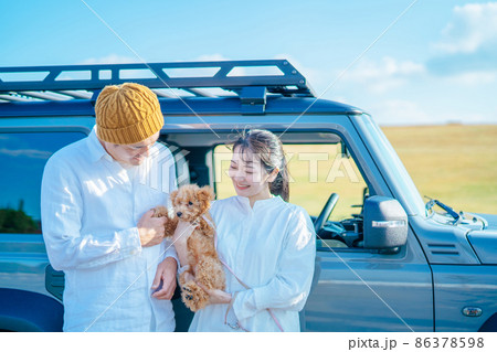 車でお出かけする犬と男女（車の前） 86378598