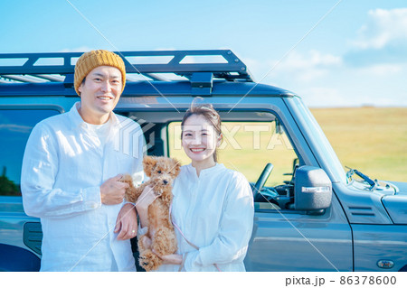 車でお出かけする犬と男女（車の前） 86378600