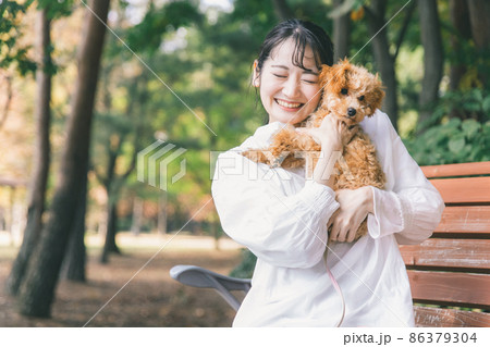 公園で犬と遊ぶ女性（抱く） 86379304