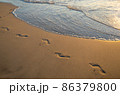 Footsteps on the golden sand with wave coming. 86379800