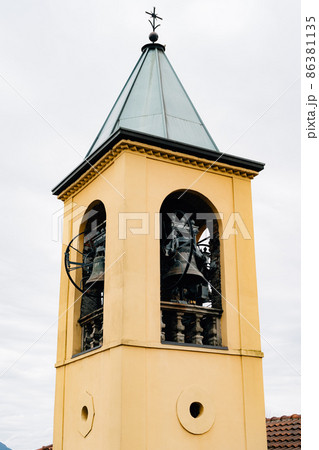 Yellow bell tower spire with vintage black bells 86381135