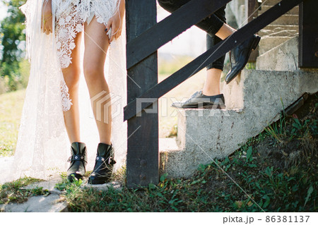 Feet of the bride and groom on the steps of the house. Close-up 86381137
