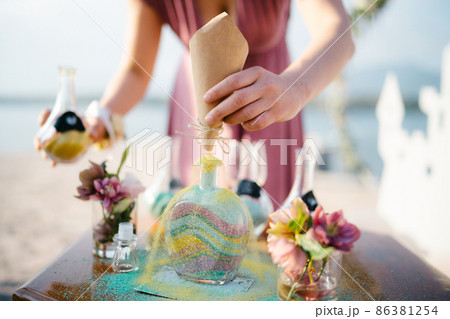 Bride pours yellow sand into a glass jar through a rolled sheet of paper 86381254