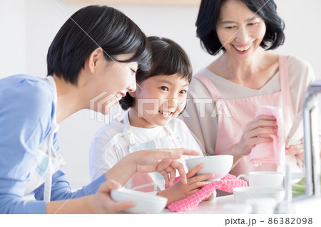 三世代ファミリー　ママとおばあちゃんと食器を拭く女の子　 86382098