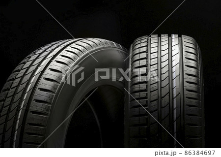 new beautiful tires on a black background, two summer car wheels with a modern tread new beautiful tires on a black background, two summer car wheels with a modern tread 86384697