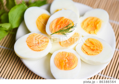 Eggs breakfast, fresh eggs menu food boiled eggs in a white plate decorated with leaves green dill background, cut in half egg yolks for cooking healthy eating 86386564