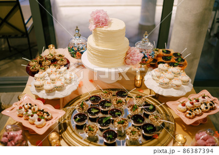 Wedding table set with bunk cake, pastries, macaroons, desserts and sweets Wedding table set with bunk cake, pastries, macaroons, desserts and sweets 86387394