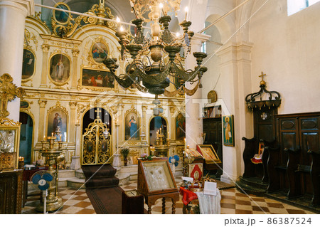 Gold chandelier hangs near the altar in the church with white columns Gold chandelier hangs near the altar in the church with white columns 86387524