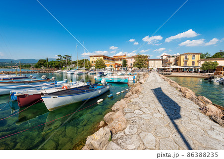 Small port of Lake Garda with moored boats - Village of Cisano Veneto Italy 86388235