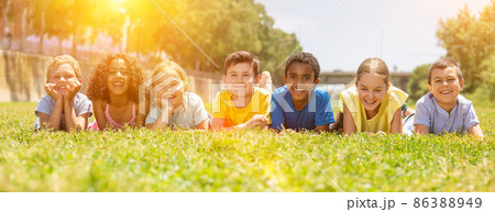 Happy team of friends children resting on grass at sunny day Happy team of friends children resting on grass at sunny day 86388949