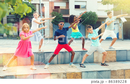 Group of tweenagers performing street dance choreography outdoors Group of tweenagers performing street dance choreography outdoors 86389228