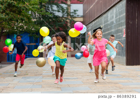 Children with balloons running through city streets Children with balloons running through city streets 86389291