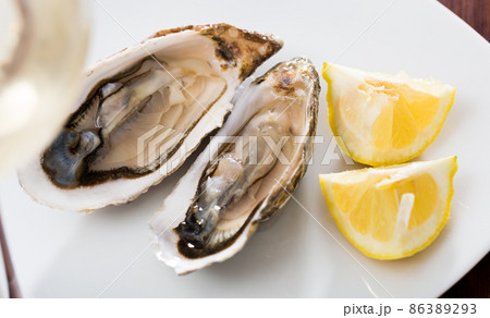 Tasty oysters with lemon on plate top view Tasty oysters with lemon on plate top view 86389293