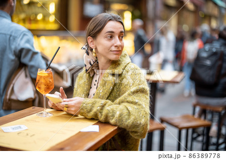 Woman with a cocktail at outdoor bar or restaurant in Bologna city 86389778