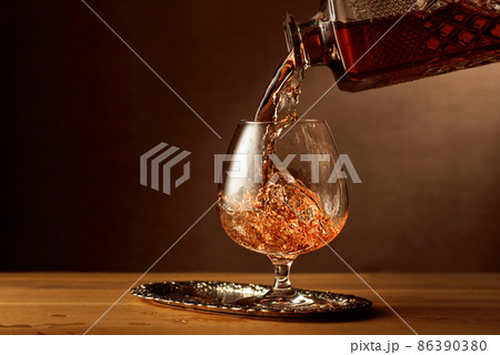 Brandy is poured into a snifter glass. 86390380