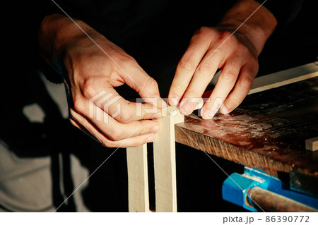 Carpenter at workbench nails down small wooden box. Hands of worker with old axe. Authentic workflow 86390772