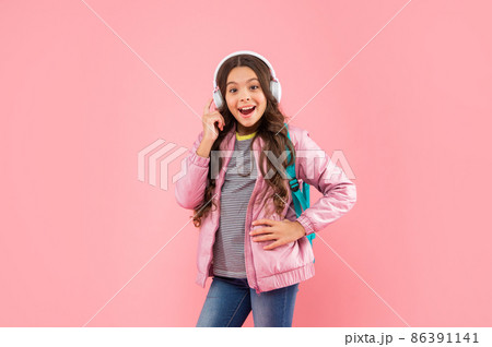amazed child listen music in headphones and carry backpack on pink background, education 86391141