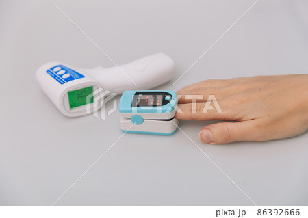 Pulse oximeter and thermometer gun on white background. Infrared isometric thermometer gun to check body temperature for virus symptoms. Measuring oxygen saturation, pulse rate and oxygen levels. 86392666