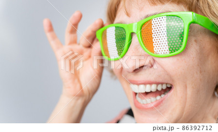 Portrait of smiling elderly woman wearing glasses with ireland flag. 86392712