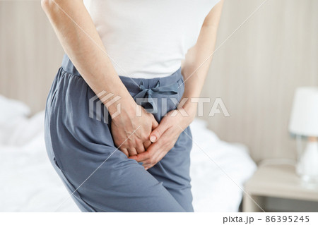 Cystitis in a woman. A young woman has a pain in the lower abdomen, she holds her stomach with her hand. 86395245
