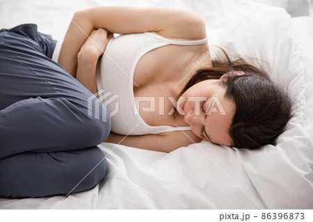 Cystitis in a woman. A young woman has a pain in the lower abdomen, she holds her stomach with her hand. 86396873