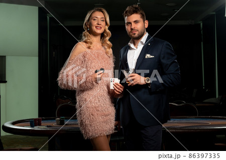 Successful girl and man winning poker game standing near gaming table in casino Successful girl and man winning poker game standing near gaming table in casino 86397335