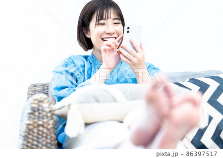 ソファでスマホを使う若い女性 ソファでスマホを使う若い女性 86397517